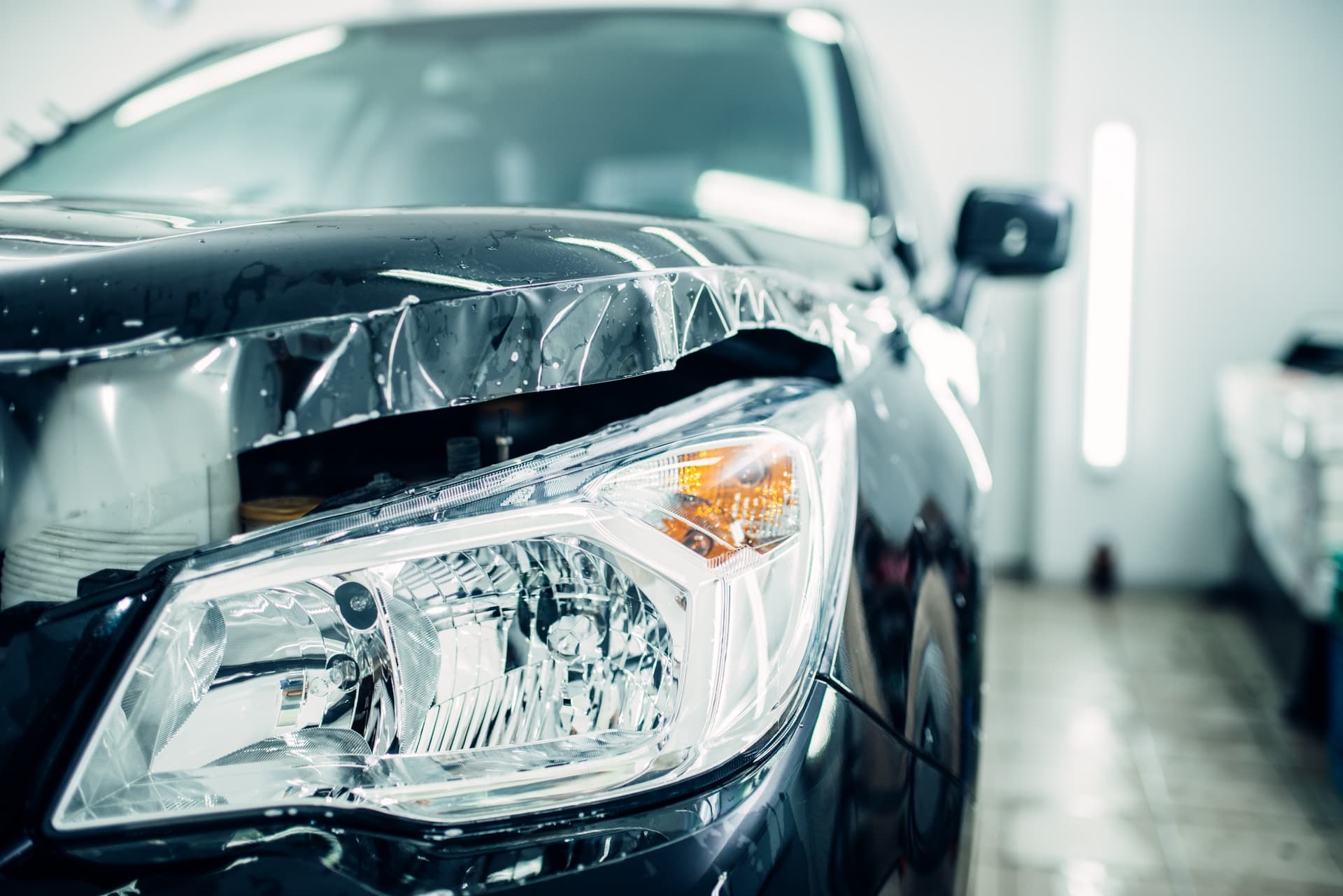 Automotive repair in progress on the front section of a car, including the headlight area