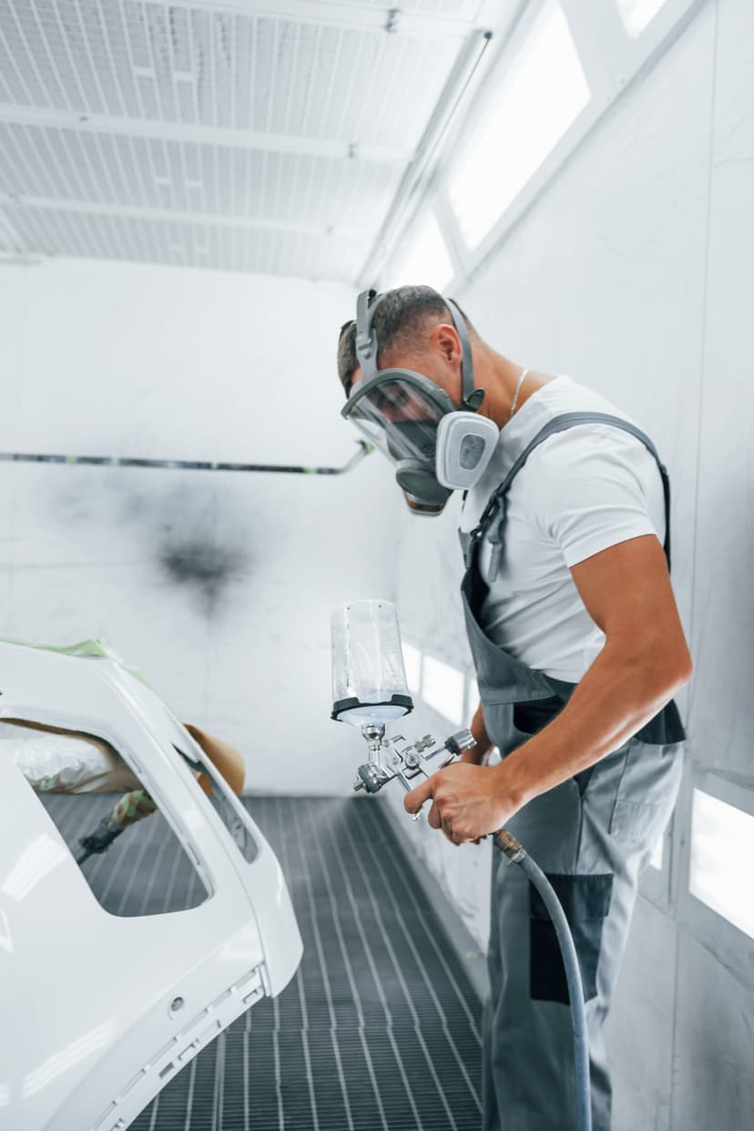 Technician applying paint to white car in spray booth at Cool Cars, Swanmore, SO32 2PB